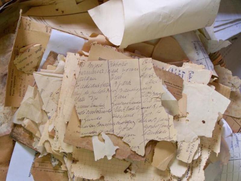 A pile of old degraded paper with handwritting on it