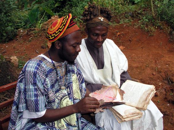 Idrissou Njoya and Nji Mapon examine Mapon's endangered manuscript collection